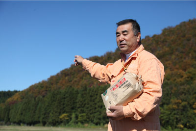 麓を指差す生産者